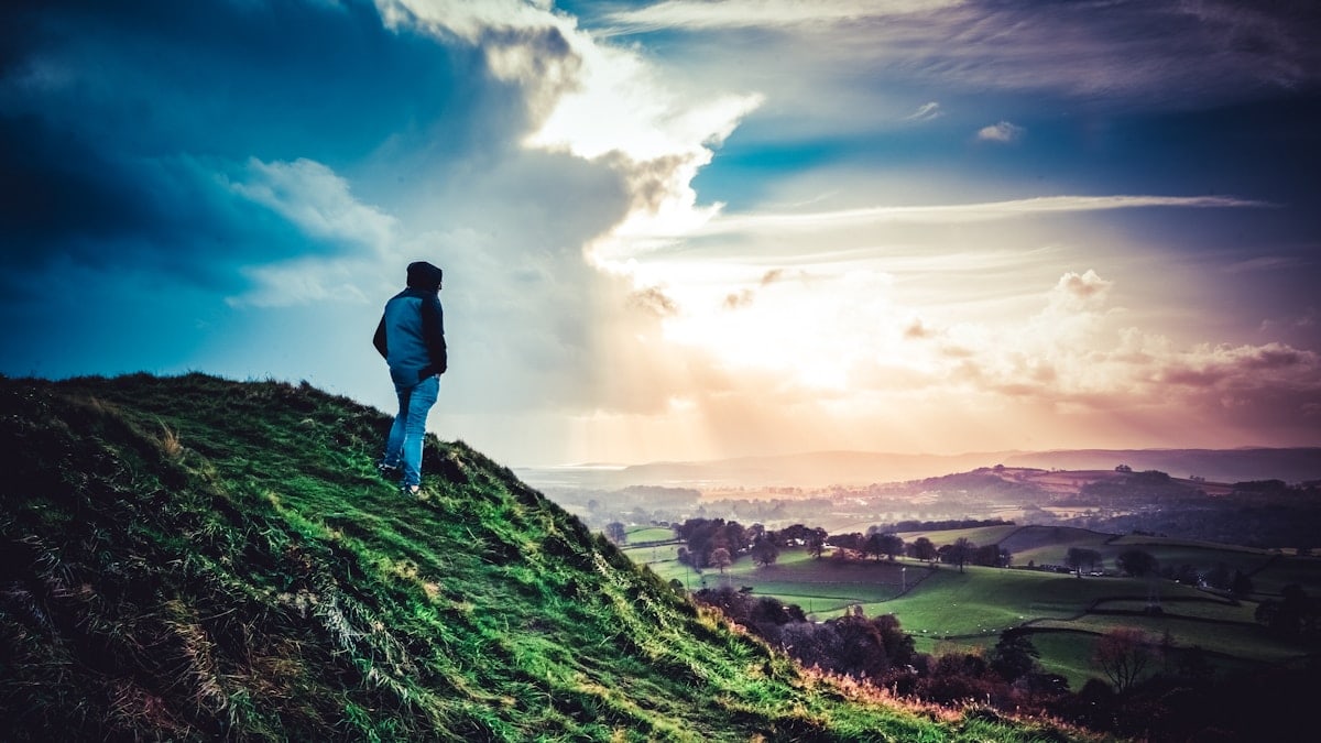 man in blue jacket standing on green grass field during daytime